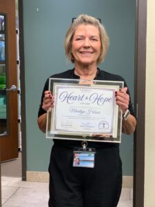 Nurse Marilyn Hibser holding the Heart of Hope Award, recognizing her exceptional dedication to hospice care at Generations Health Care.