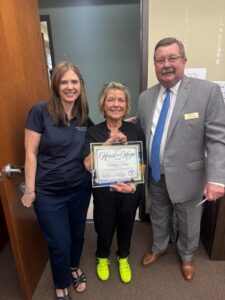 Marilyn Hibser, RN, holding the Heart of Hope Award certificate, flanked by two colleagues at Generations Health Care, celebrating her recognition for exceptional hospice care.